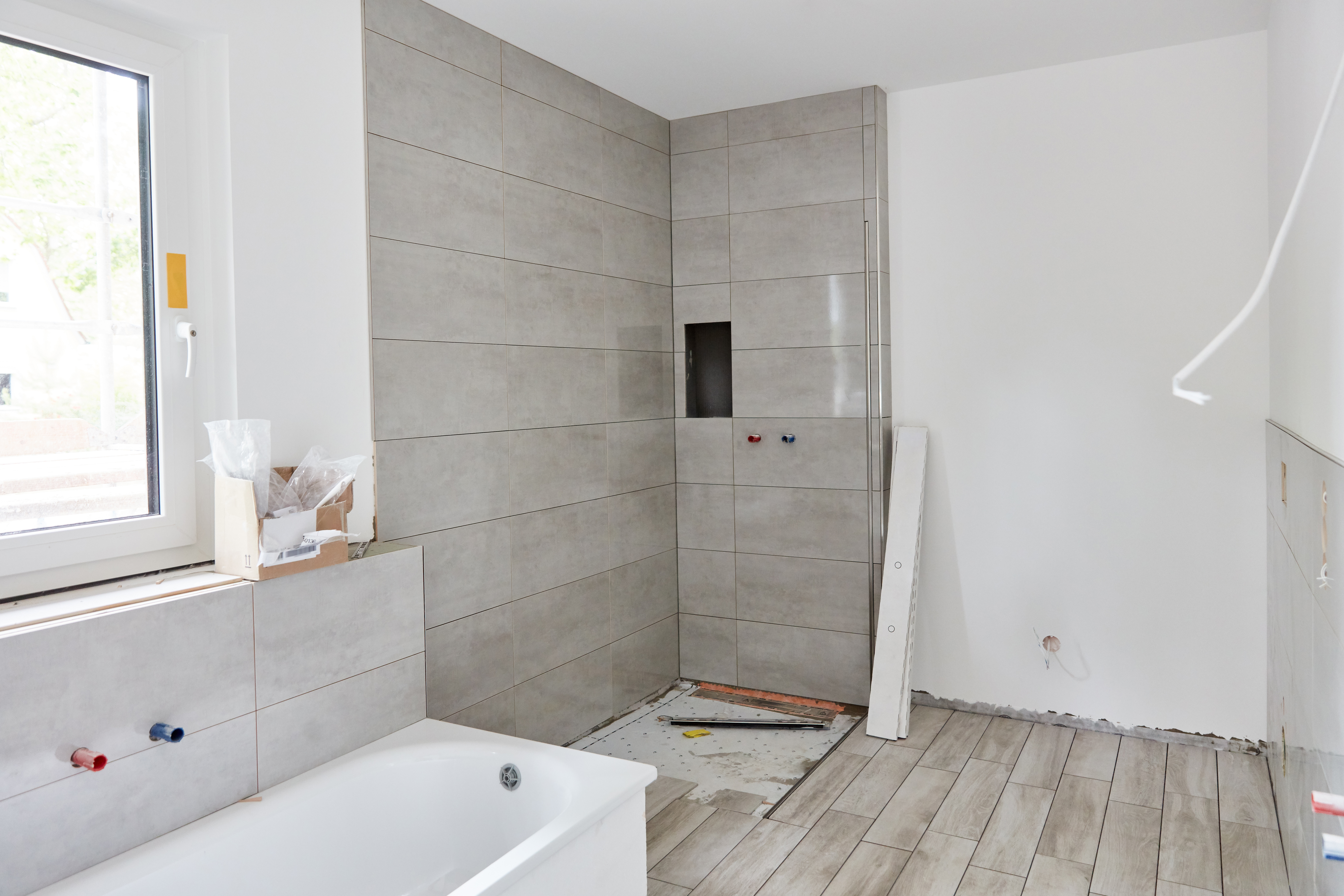 Neues Badezimmer nach Badsanierung mit Dusche und Badewanne mit neuen Fliesen nach Malerarbeiten bei Hausbau